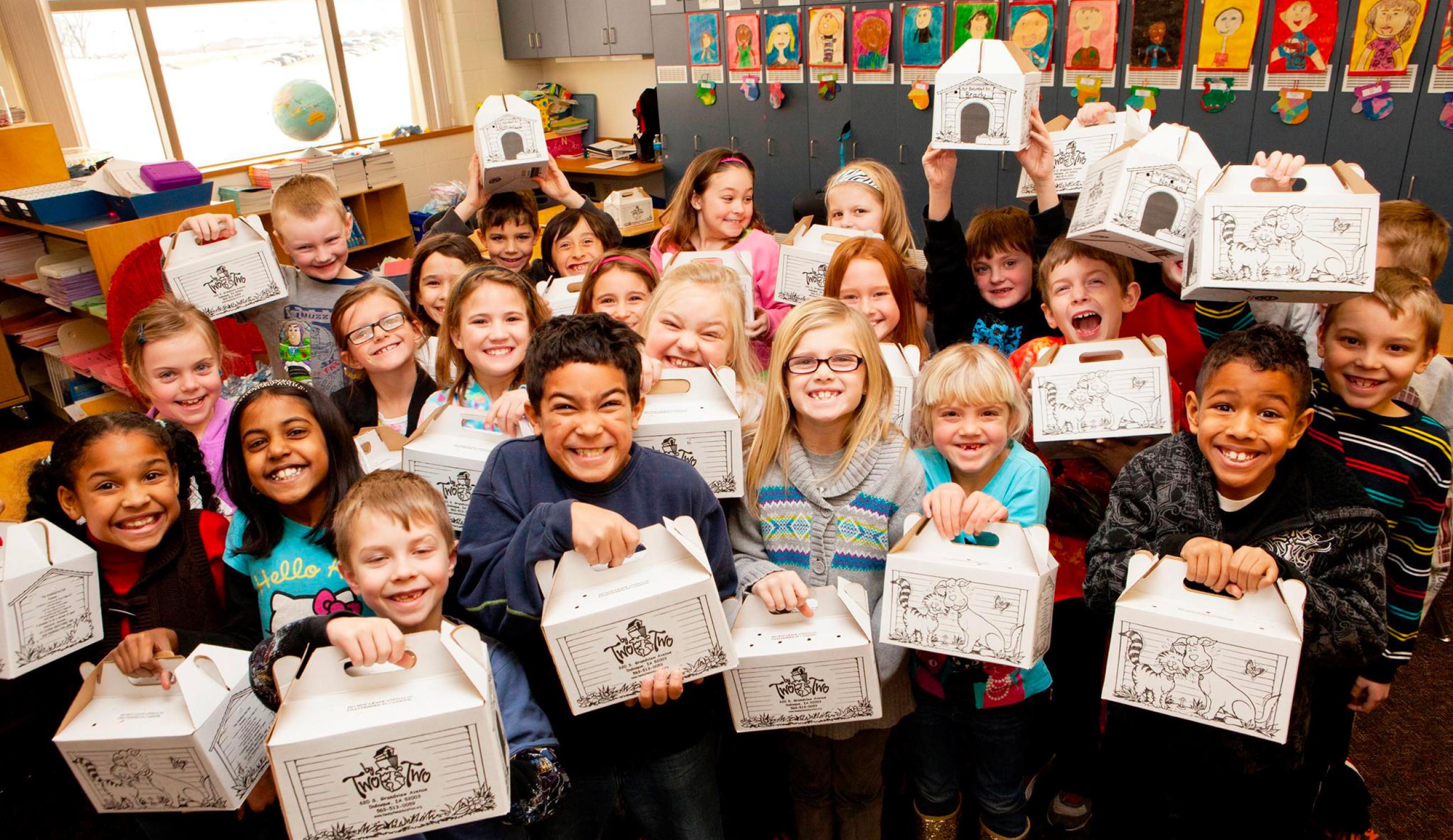 Children in classroom holding TwoByTwo boxes that have stuffed animals inside